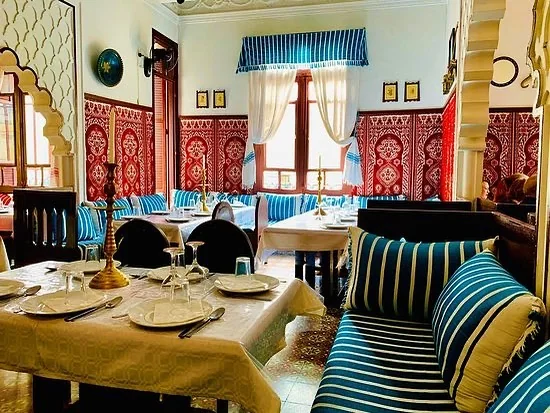 Salle dressée du Restaurant Hamadi avec banquettes rayées et tables nappées de blanc.