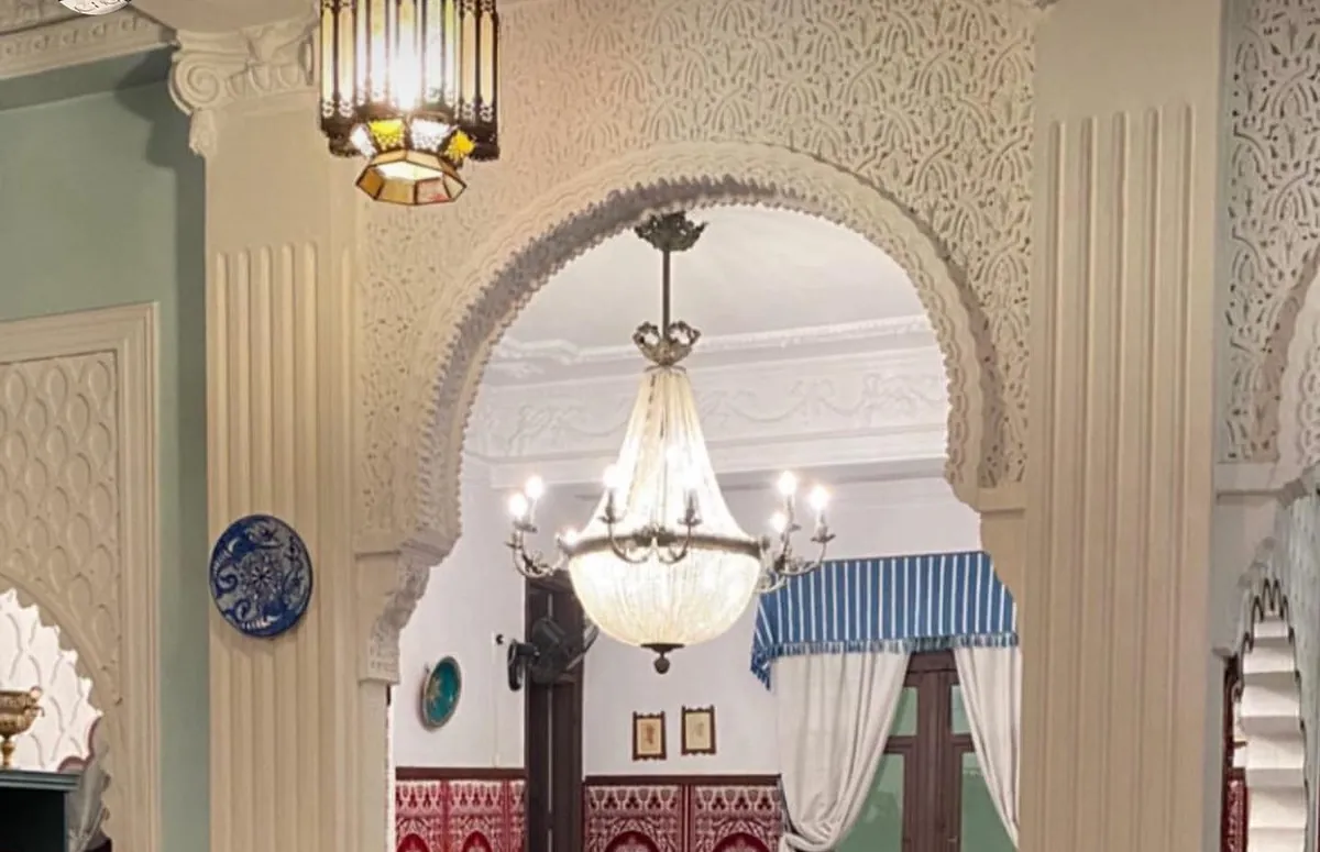 Grand salon du Restaurant Hamadi : arc en plâtre sculpté, lustre en cristal et lanterne marocaine.